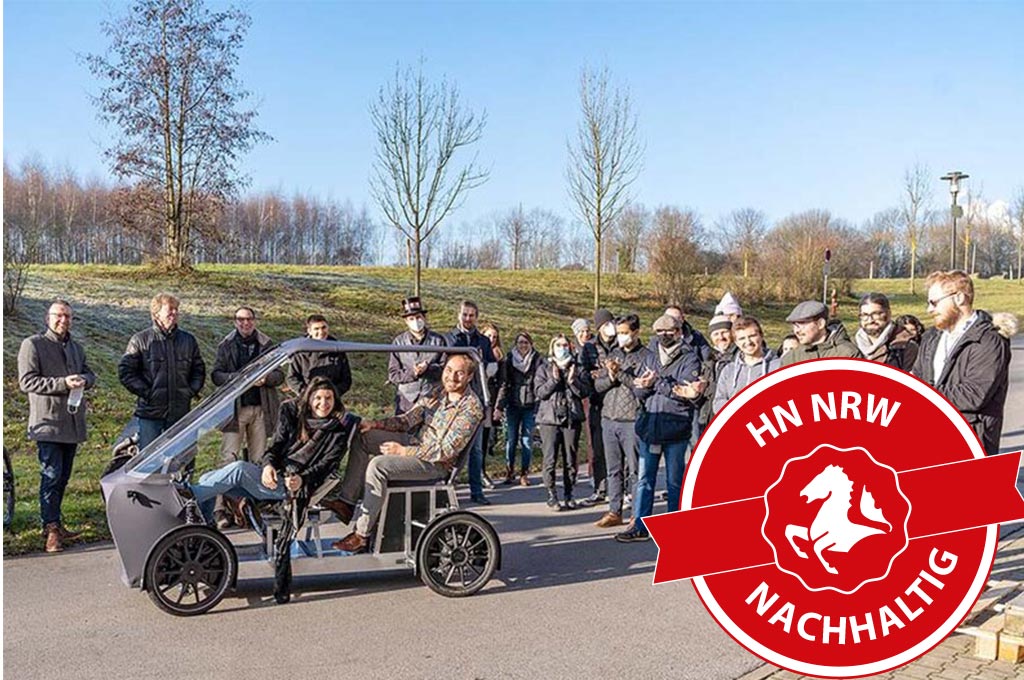 Helen Kessel und Michael Roch (im Fahrradauto vorne und hinten) stellen das fair.be der internen Hochschulöffentlichkeit an der Westfälischen Hochschule in Gelsenkirchen vor.