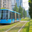 Ein Bild von einer blauen Straßenbahn an einer begrünten Bahnspur